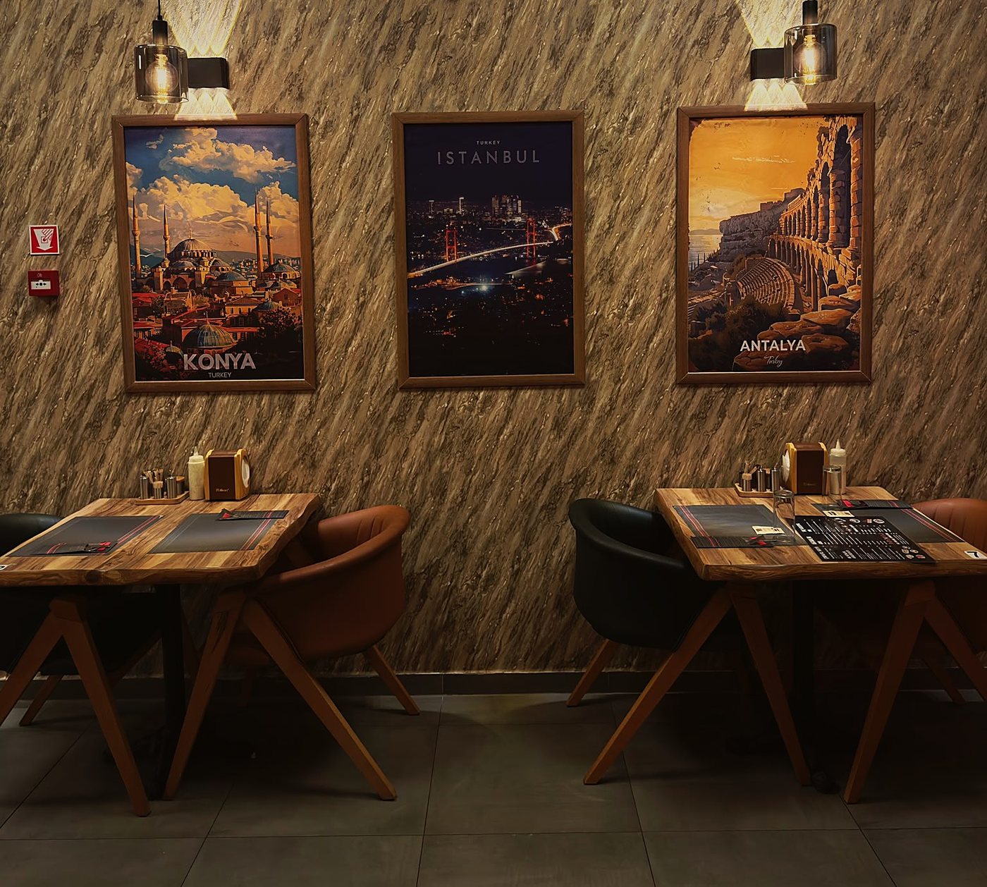 Twee tafeltjes onder drie ingekaderde affiches van Konya, Istanbul en Antalya op een marmerwand