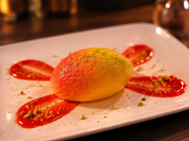 Fruitdessert in de vorm van een mango, met aardbeiensaus en pistache